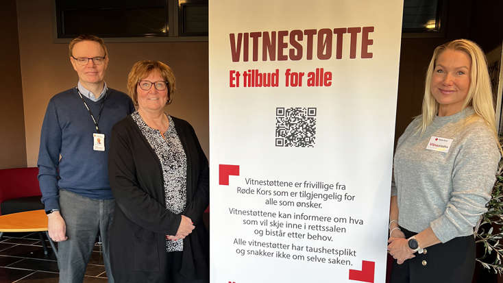 I midten på bildet står en rollup med informasjon om vitnestøtte. Til høyre står Nina Dobloug og til venstre står Jan Ferger og Mona Kristiansen.