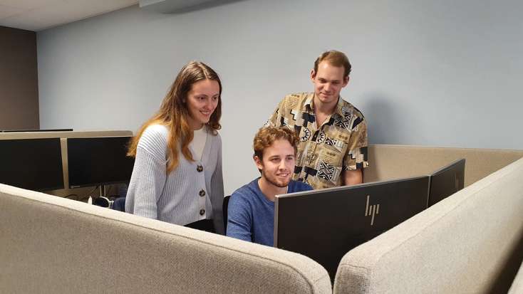 Bilde av sommerstudentene foran en PC.