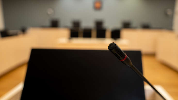 Nærbilde av mikrofon og PC-skjerm i rettssal.
